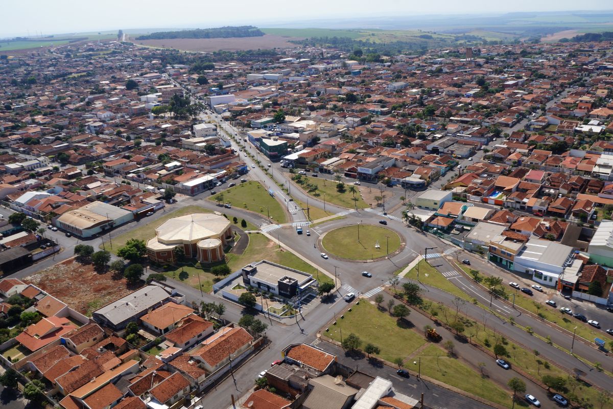 Vista aérea de Américo Brasiliense, com bairros residenciais, áreas verdes e vias urbanas em destaque sob céu.