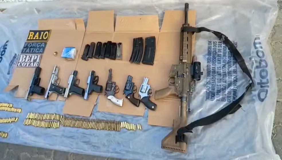 Imagem exibe diversos fuzis de modelos diferentes empilhados no chão após a operação policial, evidenciando o alto poder de fogo do grupo criminoso.